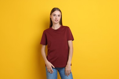 Photo of Woman wearing stylish burgundy t-shirt on yellow background