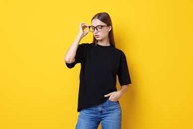Photo of Woman wearing stylish black t-shirt on yellow background