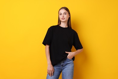 Photo of Woman wearing stylish black t-shirt on yellow background