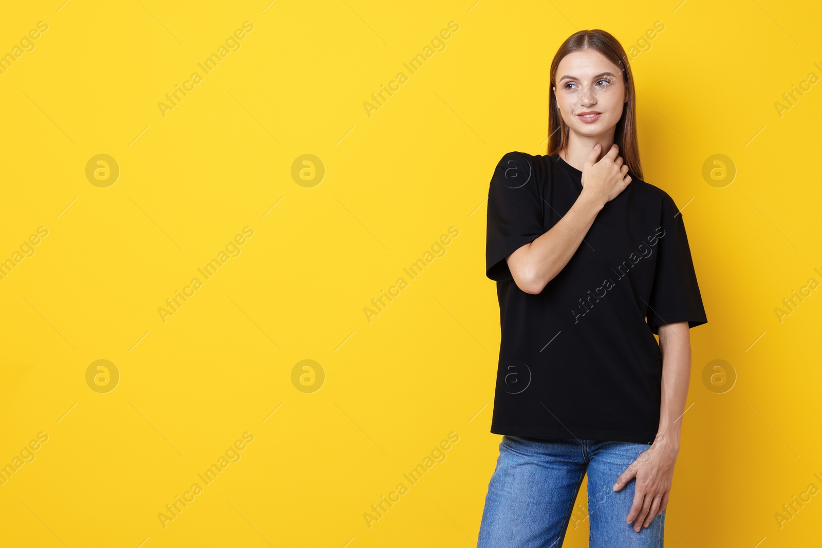 Photo of Woman wearing stylish black t-shirt on yellow background. Space for text