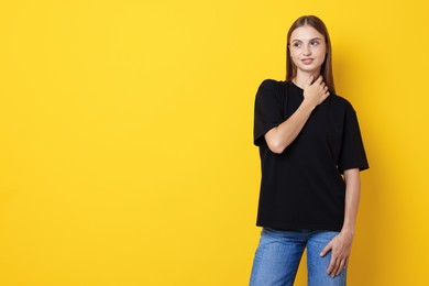 Photo of Woman wearing stylish black t-shirt on yellow background. Space for text