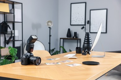 Photo of Camera, pictures and computer on wooden table in studio
