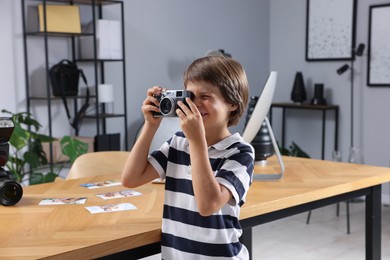 Photo of Choice of profession. Little boy with camera pretending to be photographer in studio