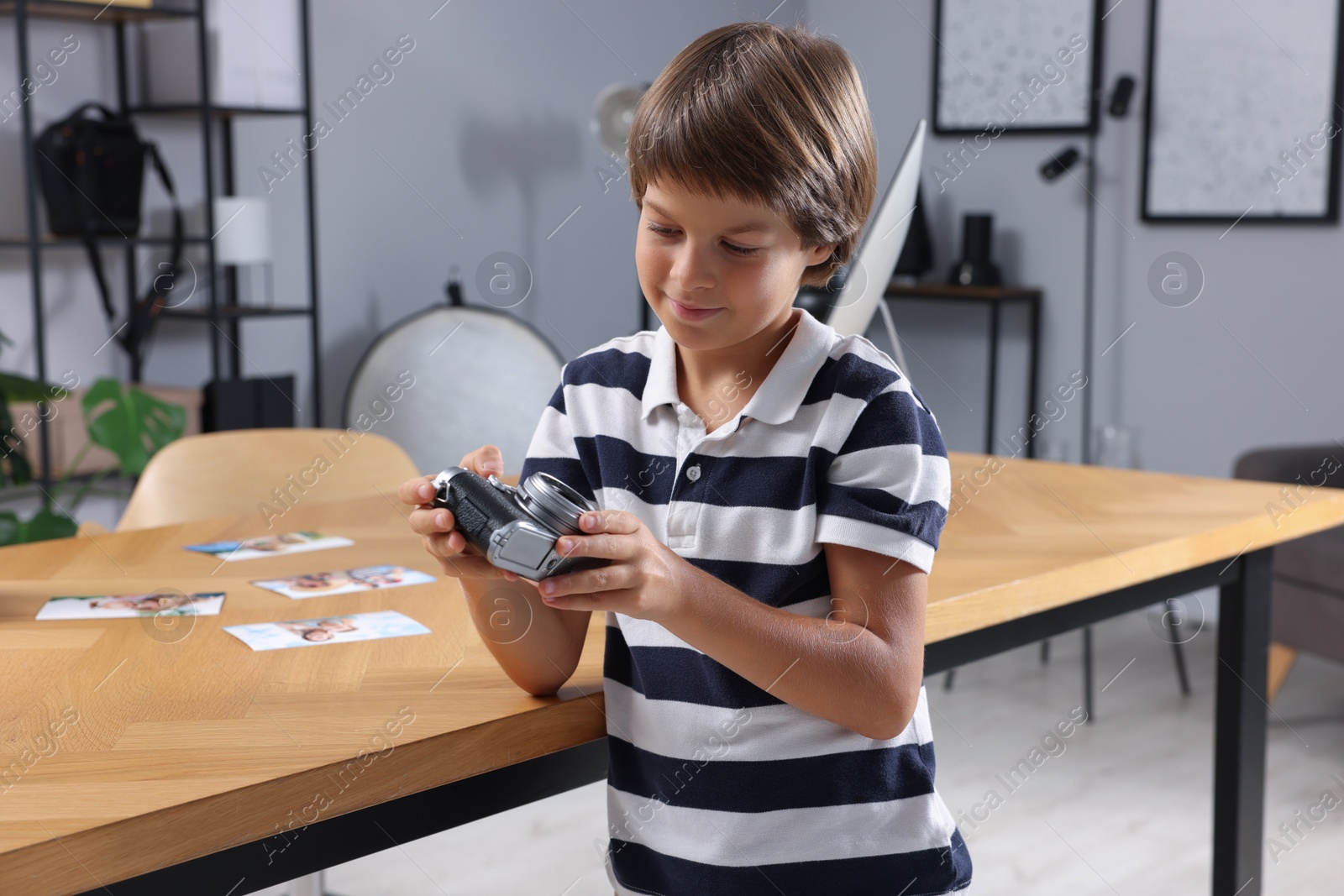 Photo of Choice of profession. Little boy with camera pretending to be photographer in studio