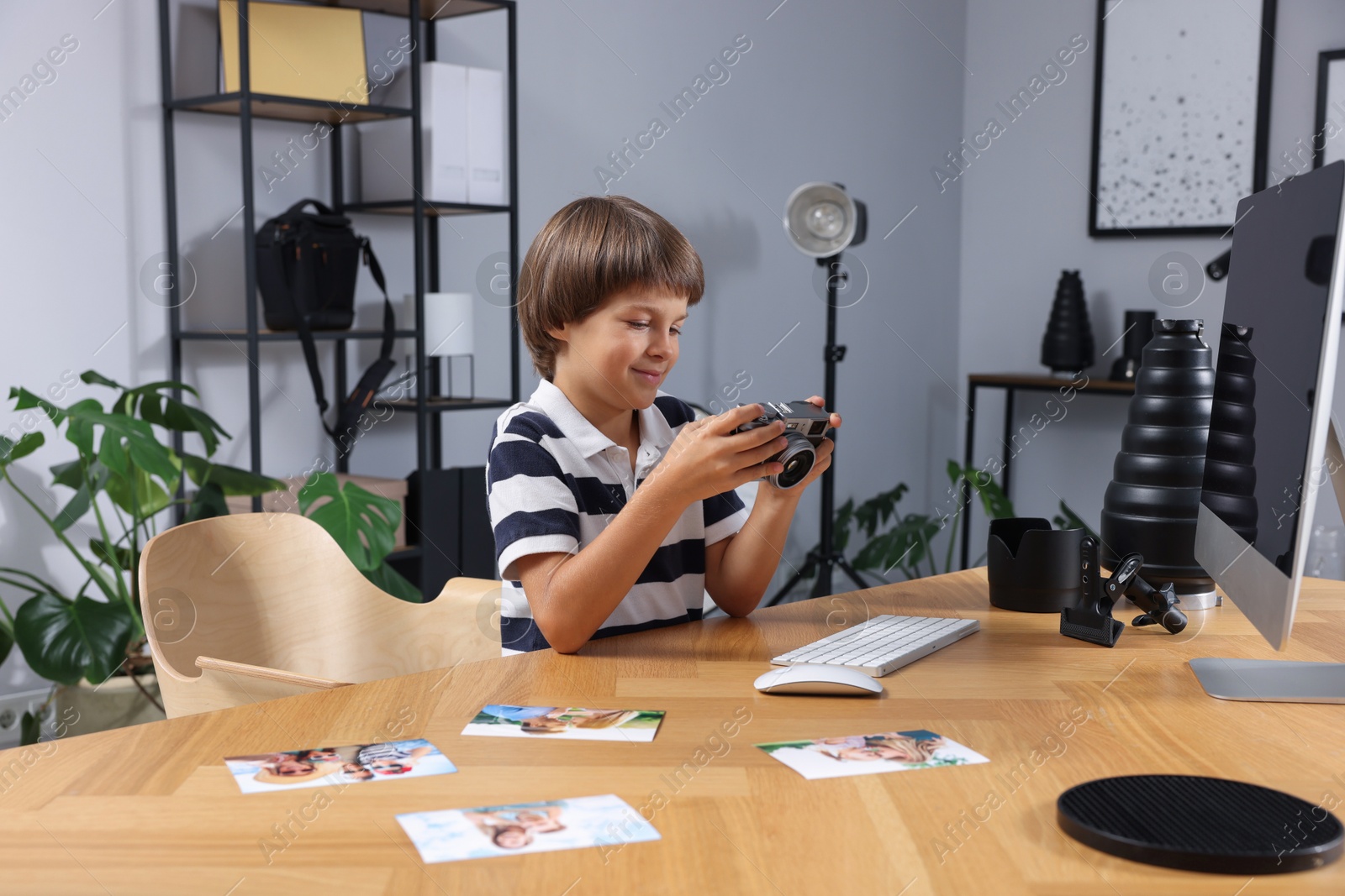Photo of Choice of profession. Little boy with camera pretending to be photographer at wooden table in studio