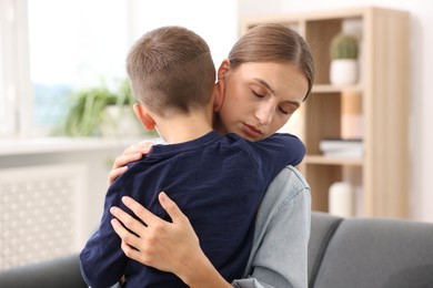 Photo of Mother supporting and hugging her upset son at home