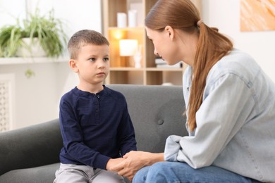 Photo of Mother supporting and holding hands with her upset son at home