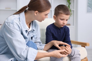 Photo of Mother supporting and holding hands with her upset son at home