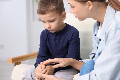 Photo of Mother supporting and holding hands with her upset son at home, closeup