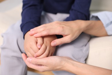 Photo of Mother supporting and holding hands with her son at home, closeup