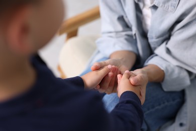 Photo of Mother supporting and holding hands with her son at home, closeup