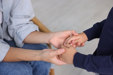Photo of Mother supporting and holding hands with her son at home, closeup