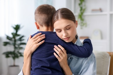 Photo of Mother supporting and hugging her upset son at home
