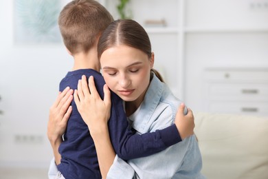 Photo of Mother supporting and hugging her upset son at home