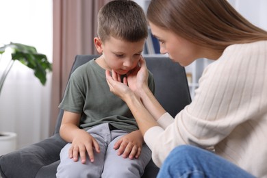 Photo of Mother supporting her upset son at home, closeup