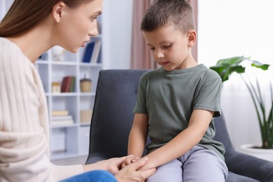 Photo of Mother supporting and holding hands with her upset son at home, closeup