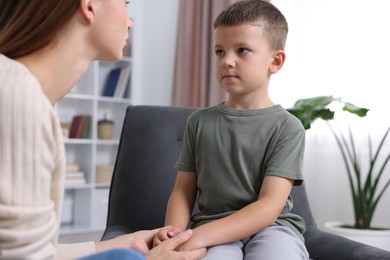 Photo of Mother supporting and holding hands with her upset son at home, closeup