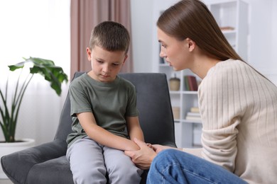 Photo of Mother supporting and holding hands with her upset son at home