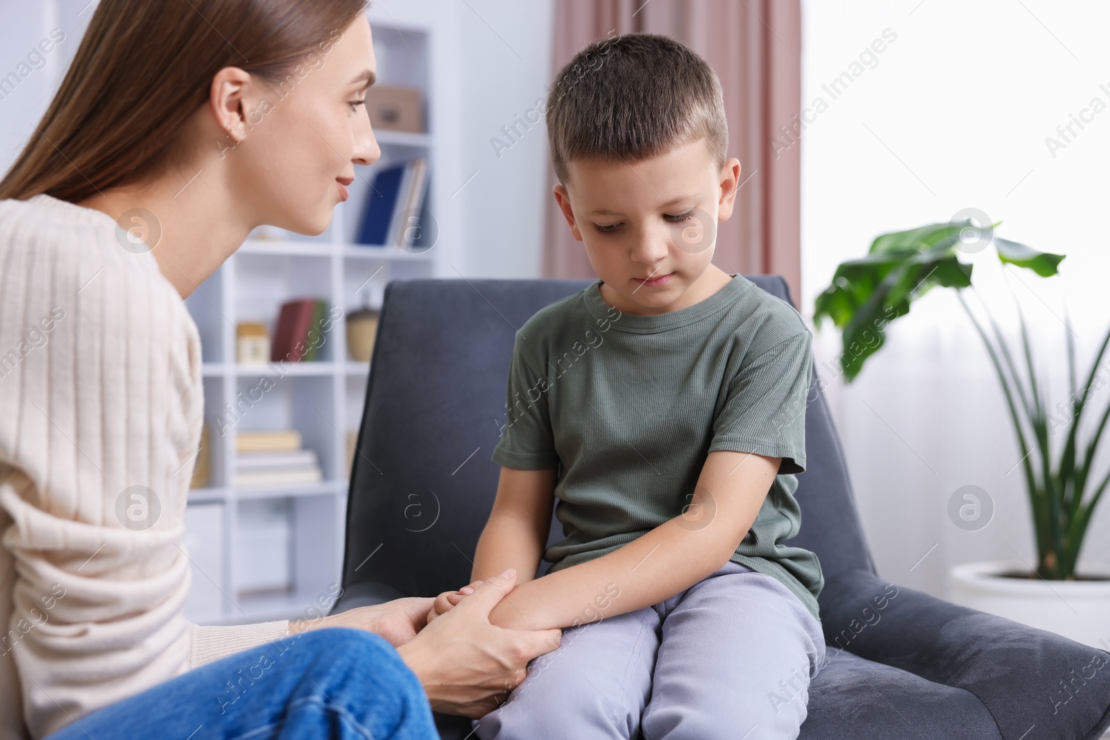 Photo of Mother supporting and holding hands with her upset son at home