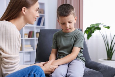 Photo of Mother supporting and holding hands with her upset son at home