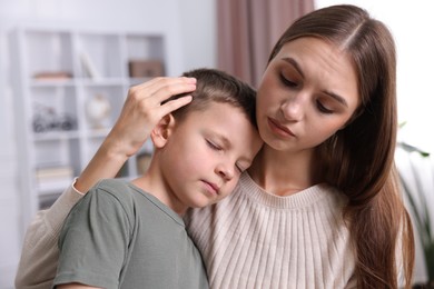 Photo of Mother supporting and hugging her upset son at home