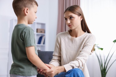 Photo of Mother supporting and holding hands with her upset son at home