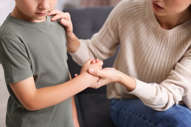 Photo of Mother supporting her upset son at home, closeup