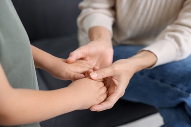 Photo of Mother supporting and holding hands with her son at home, closeup