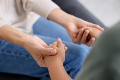 Photo of Mother supporting and holding hands with her son at home, closeup