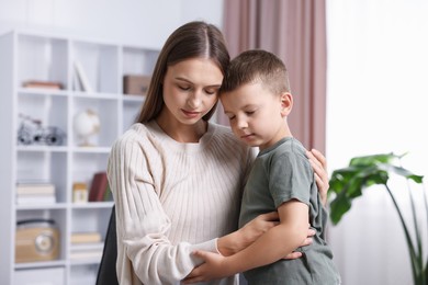 Photo of Mother supporting and hugging her upset son at home