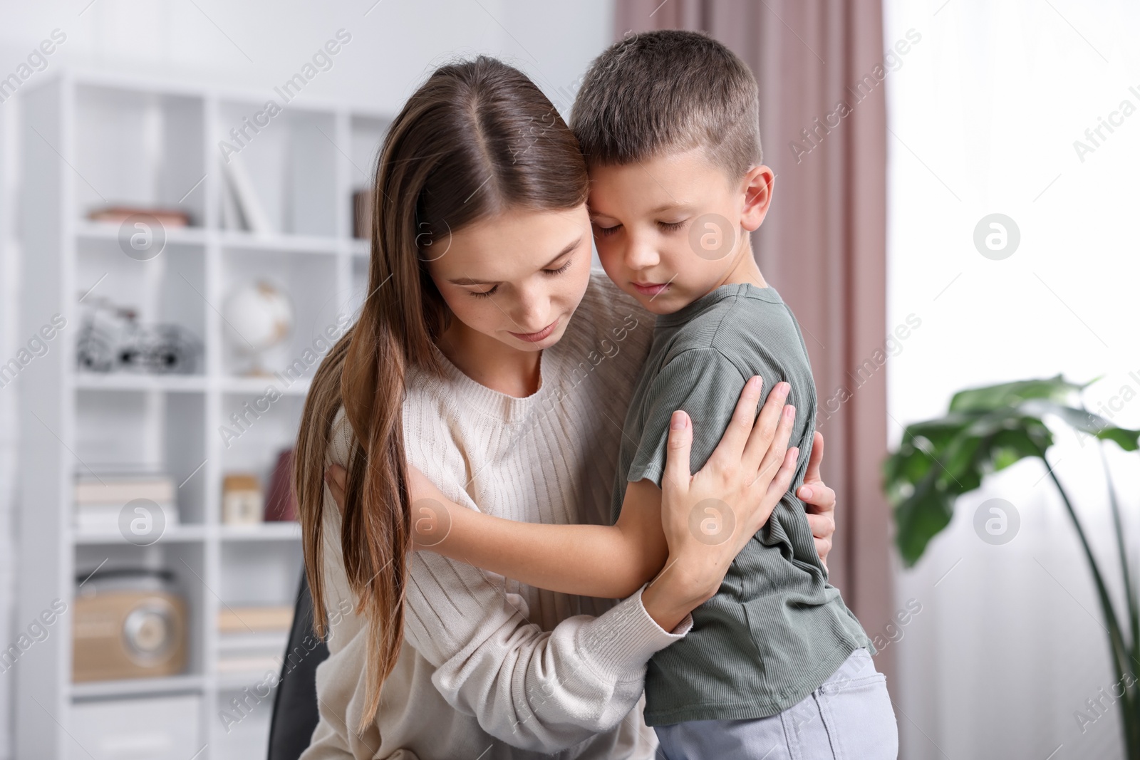 Photo of Mother supporting and hugging her upset son at home