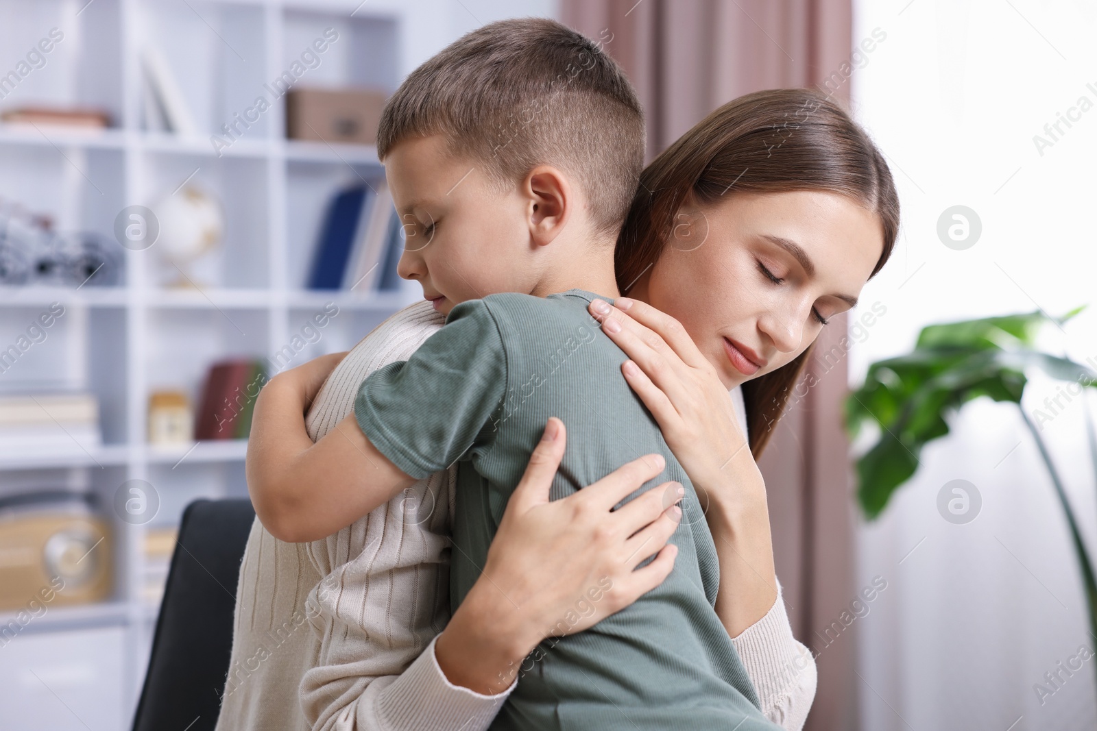 Photo of Mother supporting and hugging her upset son at home