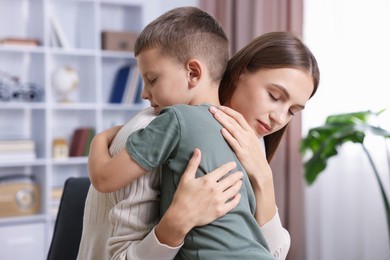 Photo of Mother supporting and hugging her upset son at home