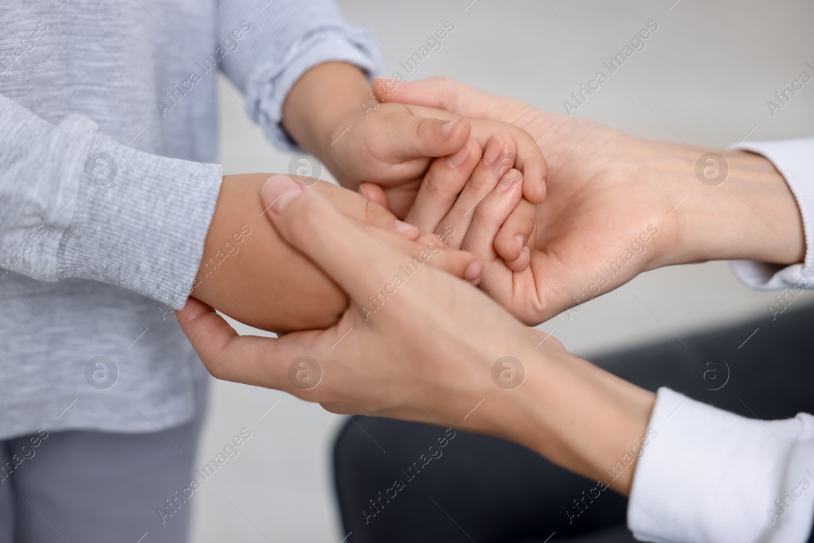 Photo of Mother supporting and holding hands with her son at home, closeup