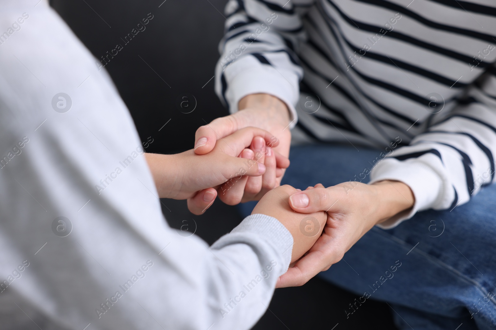 Photo of Mother supporting and holding hands with her son at home, closeup