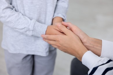 Photo of Mother supporting and holding hands with her son at home, closeup