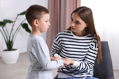 Photo of Mother supporting and holding hands with her upset son at home