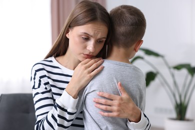 Photo of Mother supporting and hugging her upset son at home
