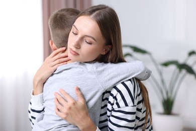 Photo of Mother supporting and hugging her upset son at home