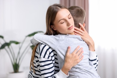 Photo of Mother supporting and hugging her upset son at home