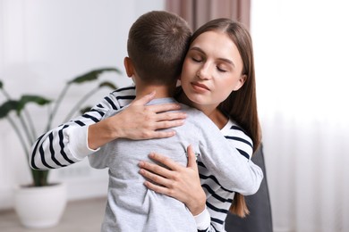 Photo of Mother supporting and hugging her upset son at home