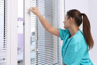 Photo of Young woman opening modern window at home