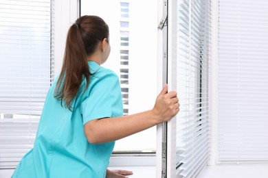 Photo of Young woman opening modern window at home