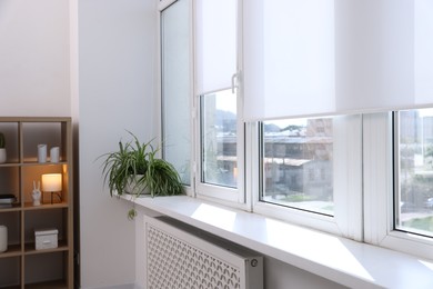Photo of Modern window with roller blinds and decor indoors
