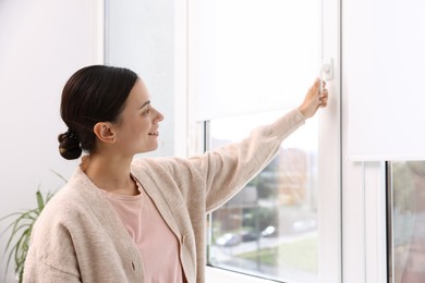 Photo of Young woman opening modern window at home