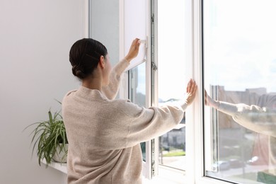 Photo of Young woman opening modern window at home