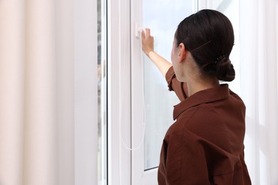 Photo of Young woman opening modern window at home