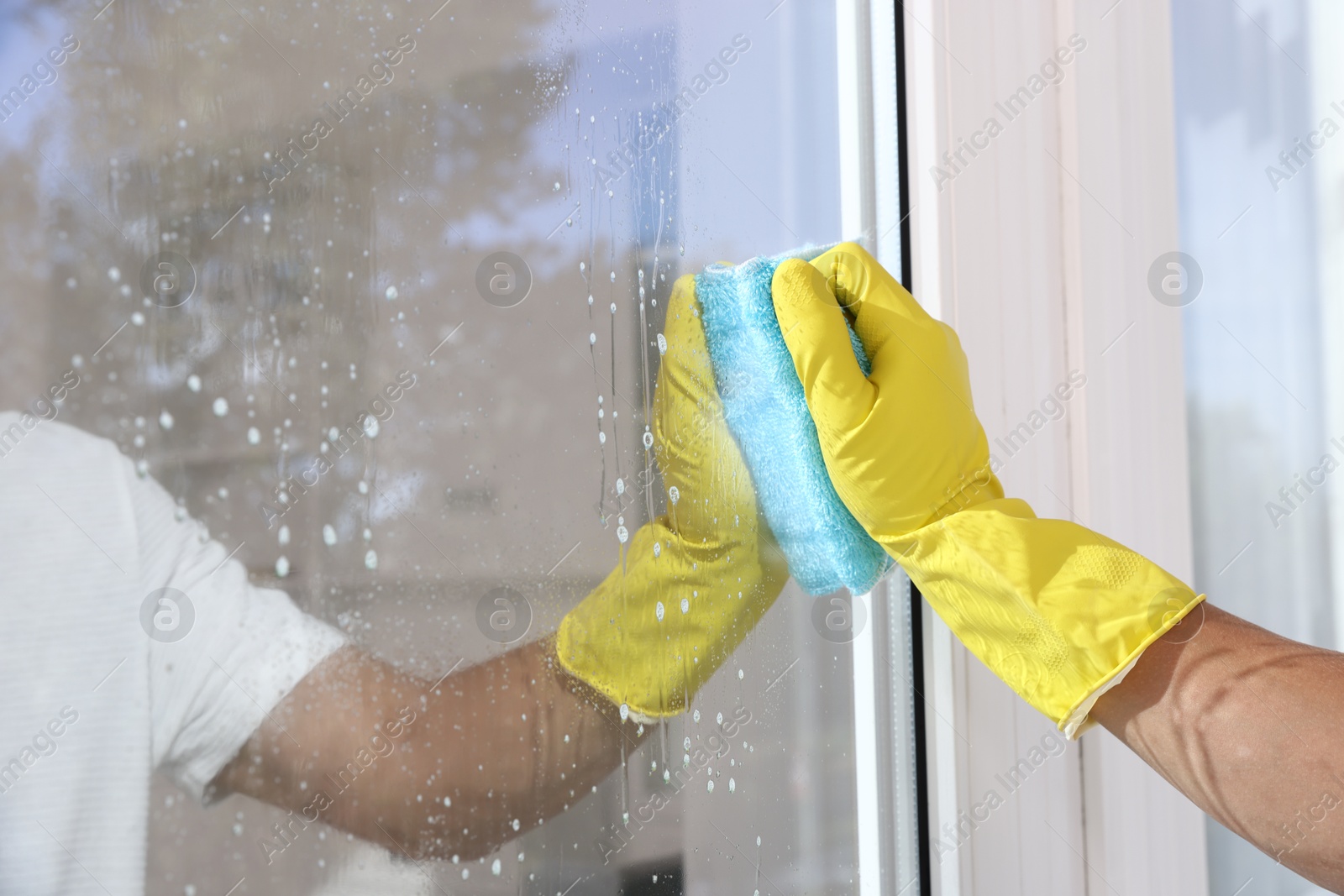 Photo of Man cleaning window with rag indoors, closeup
