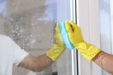 Photo of Man cleaning window with rag indoors, closeup