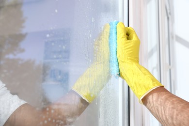 Photo of Man cleaning window with rag indoors, closeup